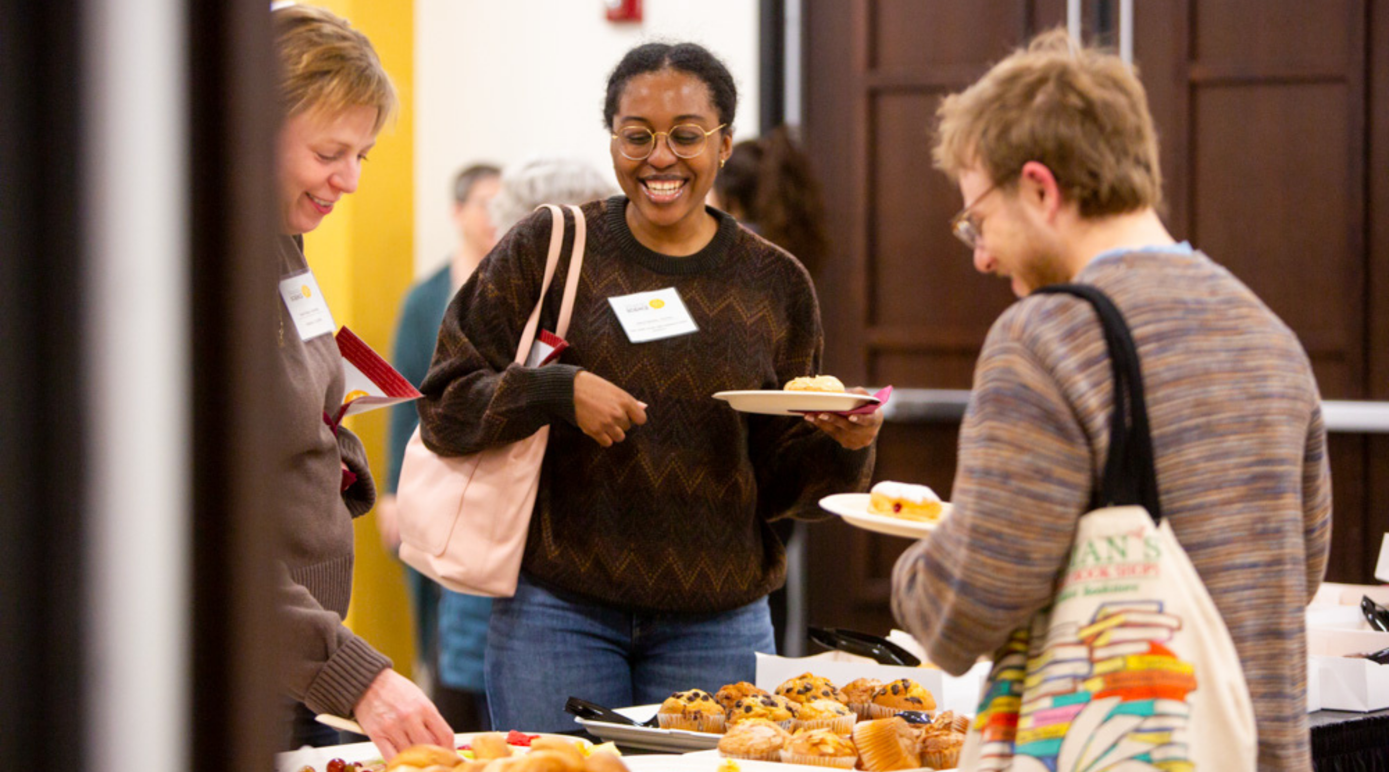 Three speaking science attendees chat and get food from a buffet at the 2025 conference.