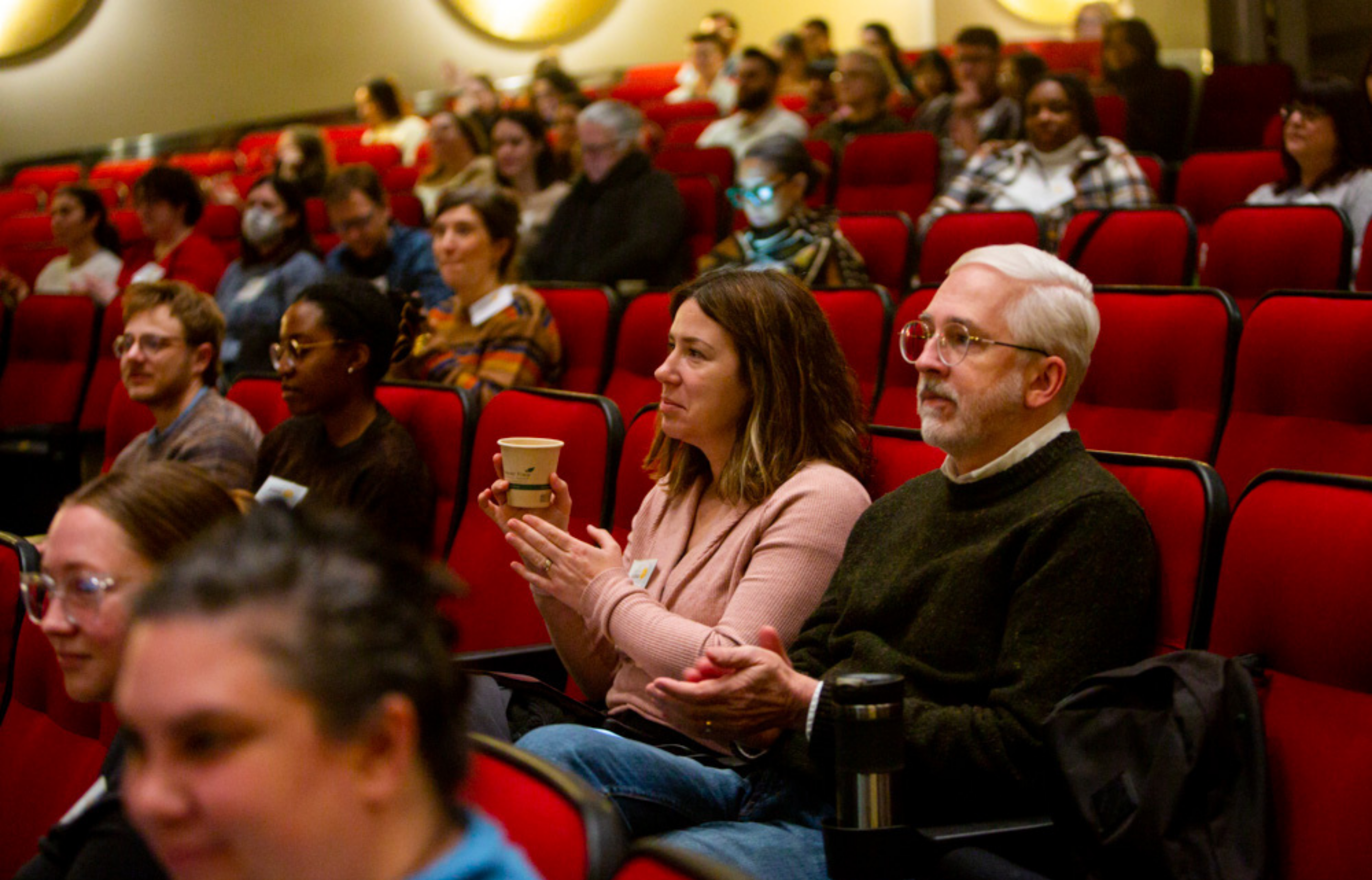 Audience members seated in a theater clap during a Speaking Science keynote.